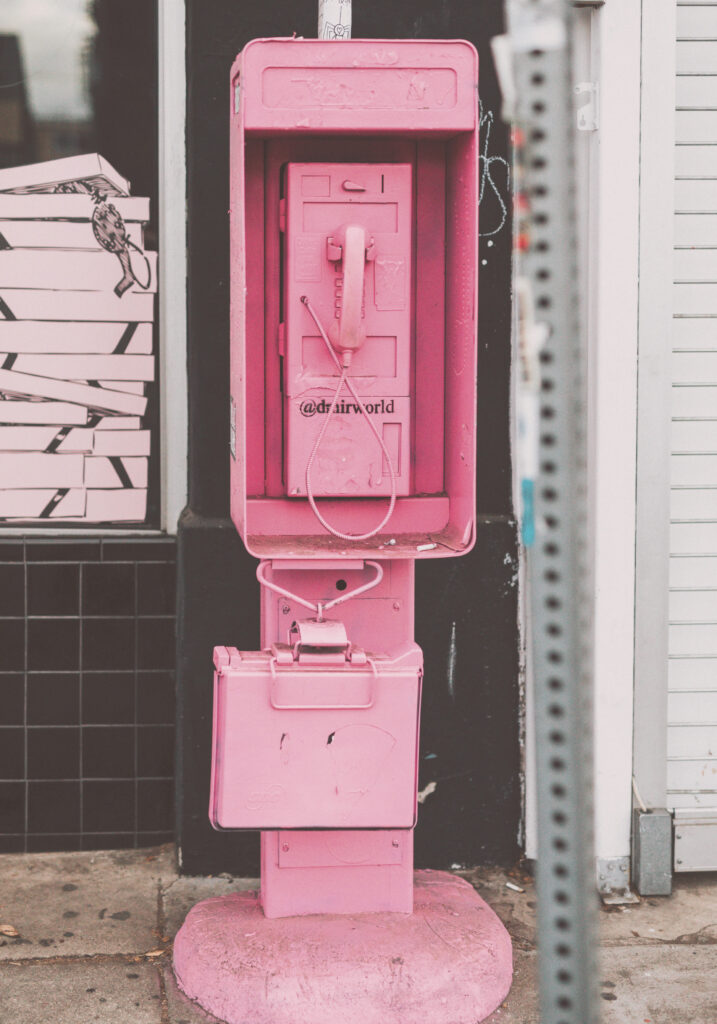 eine alte Telefonzelle pink lackiert in einer heruntergekommenen Gegend
