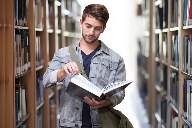 zu sehen ist ein junger Mann zwischen zwei Regalreihen einer Bibliothek