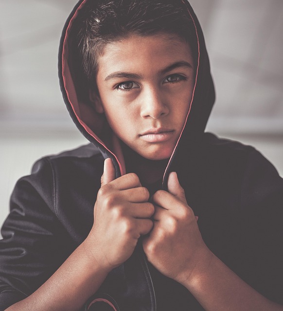 Portrait von einem Jungen mit Hoodie überm Kopf